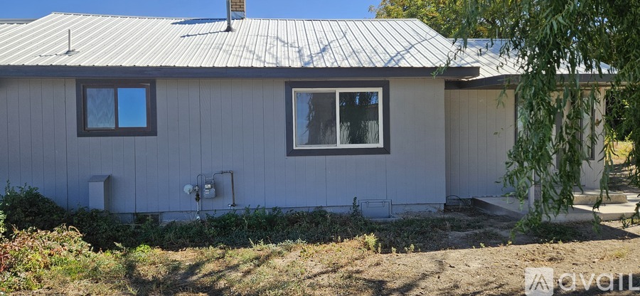 A house with a grey roof and a white wall with a window and a door.