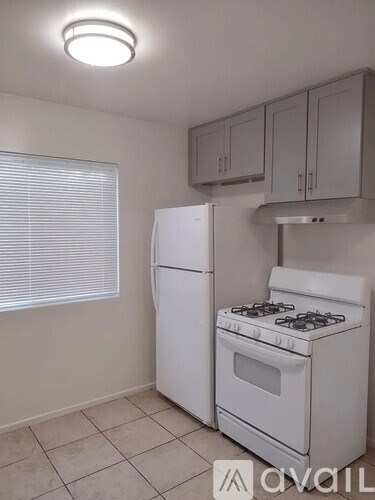 A white kitchen with a stove and refrigerator.
