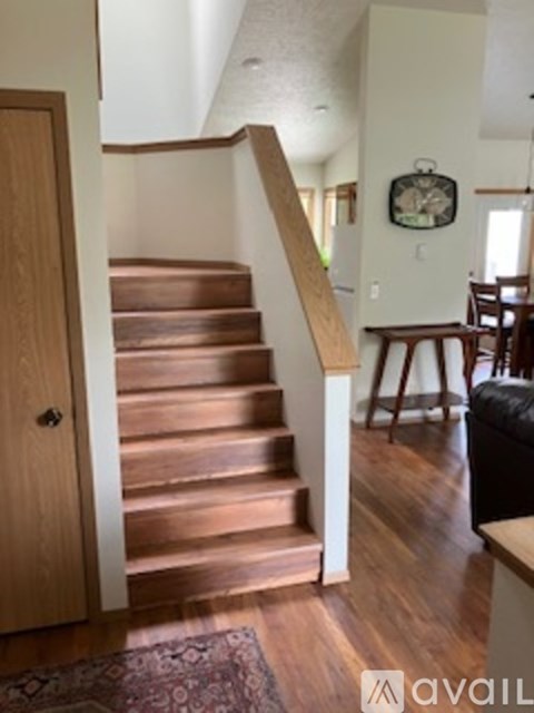 A wooden staircase with a rug on the floor.