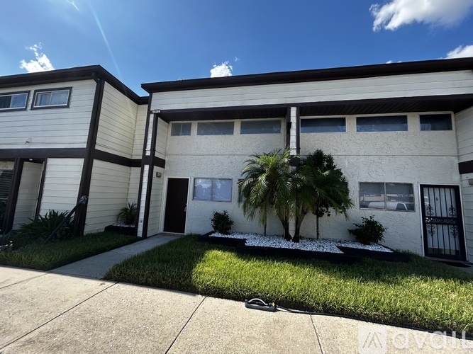 A sunny day at a two-story house with a palm tree in front.