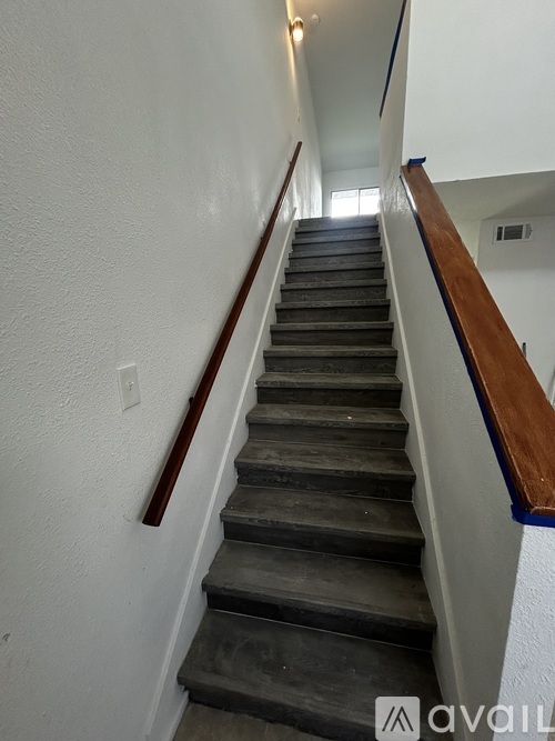 A staircase with a wooden handrail and a blue stripe on the wall.