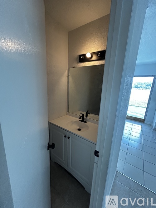 A bathroom with a sink, mirror, and cabinet.