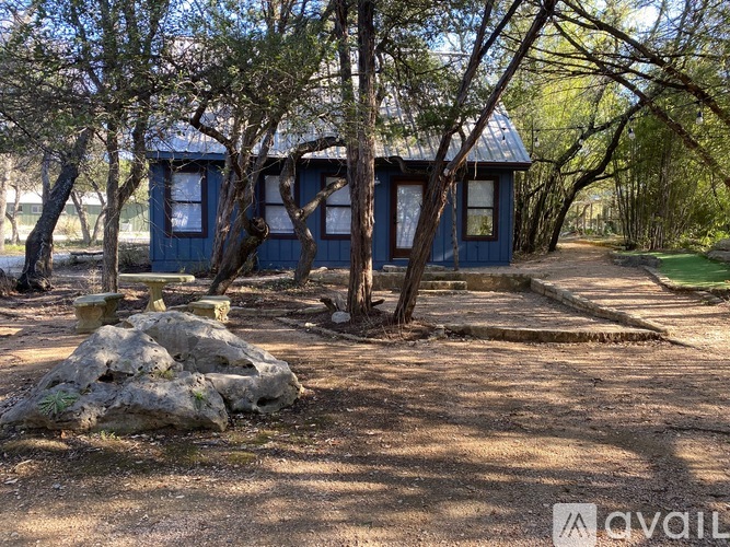 A small blue house surrounded by trees and rocks.