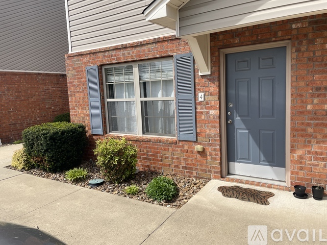 A house with a grey door and a grey window with white curtains.