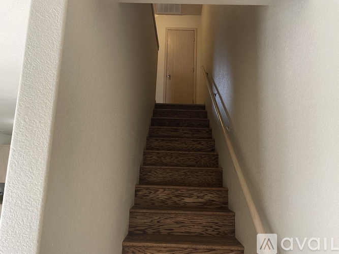 A staircase with wooden steps and a white wall on the left side.