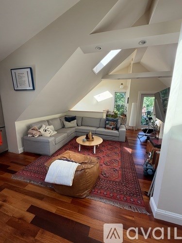 A living room with a grey couch and a red rug.