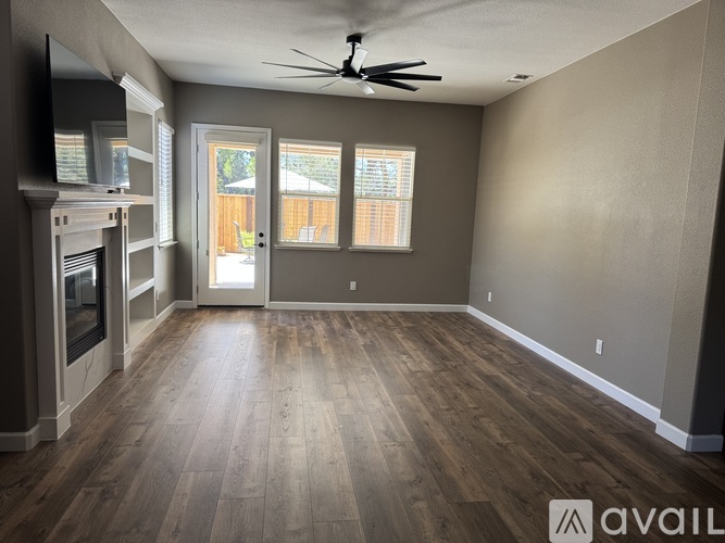 A spacious room with a fireplace and a ceiling fan.