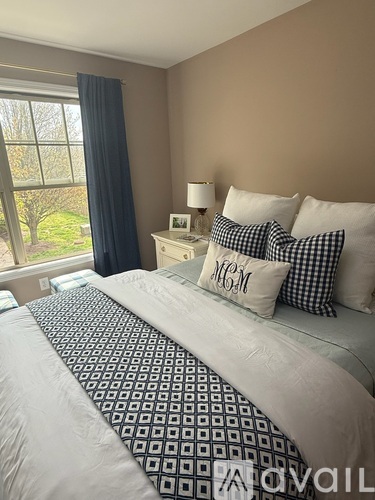 A bedroom with a large bed and a window overlooking a garden.