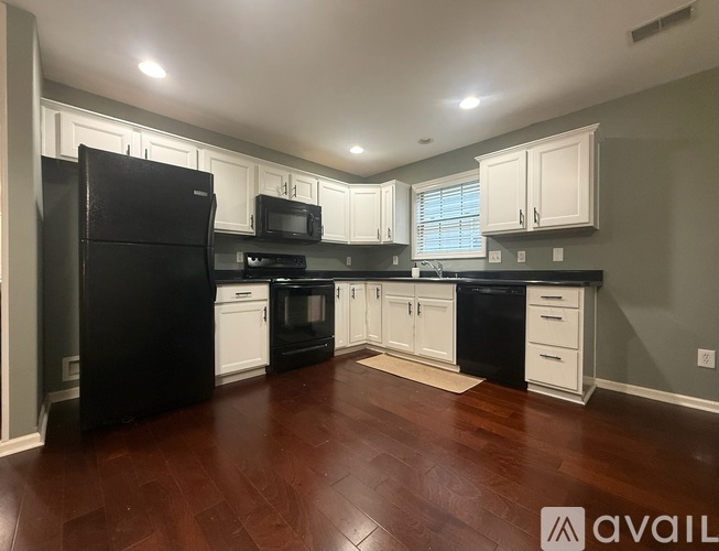 A kitchen with black appliances and white cabinets.