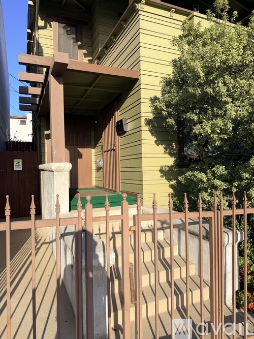 A green tree is in front of a yellow house.
