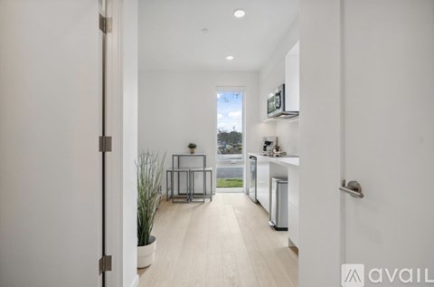 A modern kitchen with white cabinets and a wooden floor.