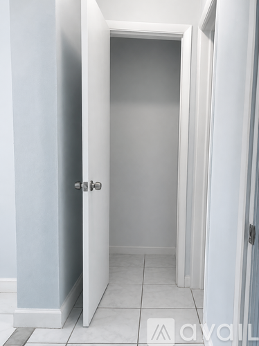 A white door is open to a white hallway.