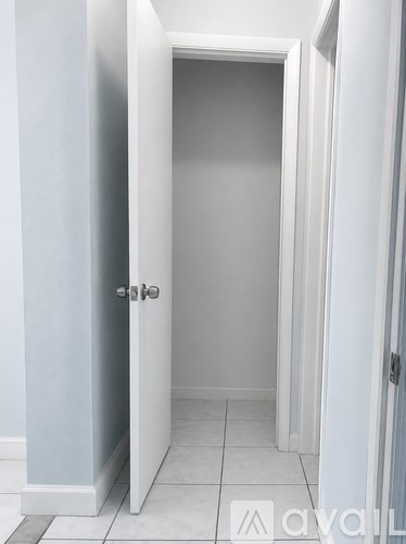 A white door is open to a white hallway.