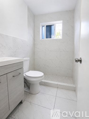 A white bathroom with a toilet, sink, and shower.