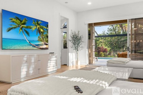 A modern bedroom with a large bed and a TV displaying a beach scene.