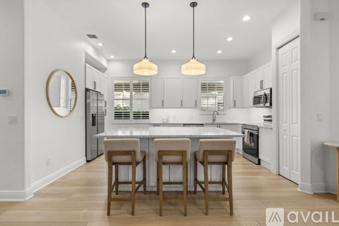 A kitchen with white cabinets and a center island with four bar stools.