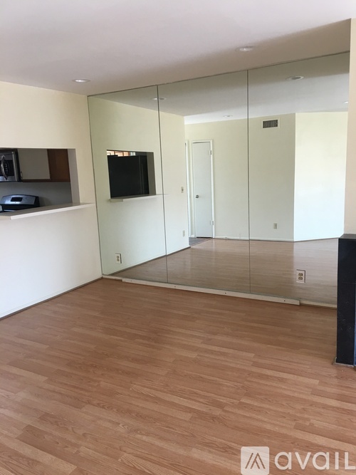 A room with wooden flooring and a glass walled room behind it.