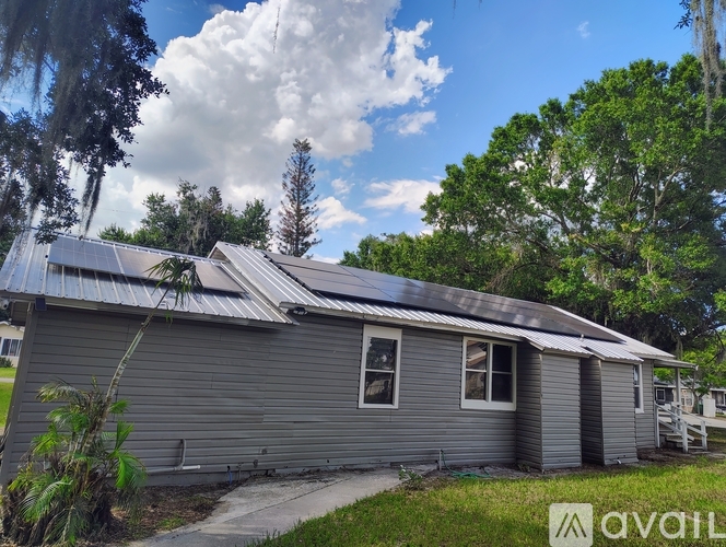 A house with a grey siding and a metal roof is for sale.