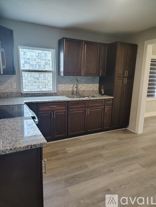 A kitchen with dark brown cabinets and a granite countertop.