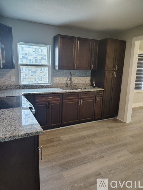 A kitchen with dark brown cabinets and a granite countertop.