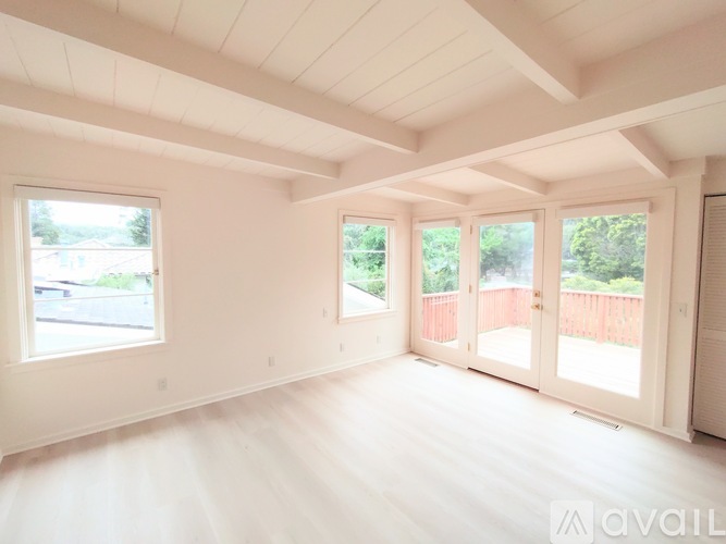 A spacious room with white walls and a large window.
