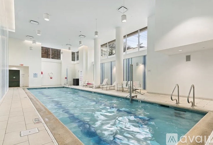A large indoor swimming pool with a blue tinted water.
