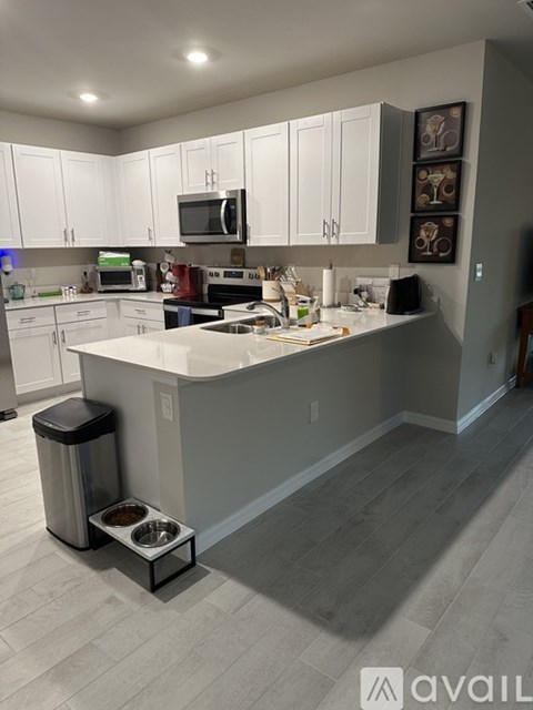 A kitchen with white cabinets and a grey island.