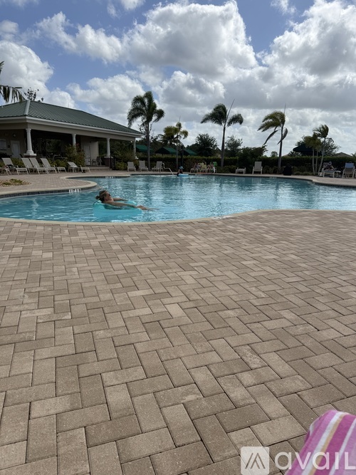 A person swims in a pool with a brick patterned floor.