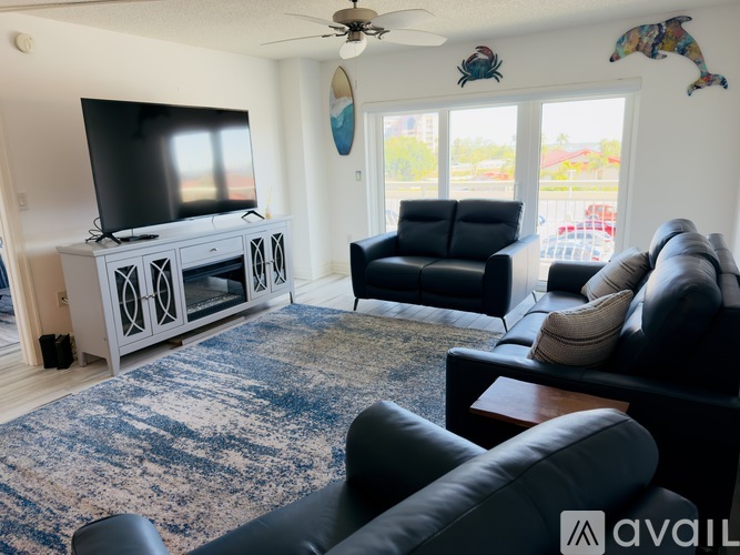 A living room with a television, two chairs, and a rug.