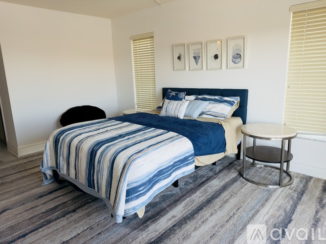 A bedroom with a bed, a round table, and a striped bedspread.