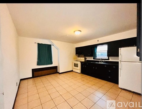 A kitchen with a white refrigerator and a microwave on a black cabinet.