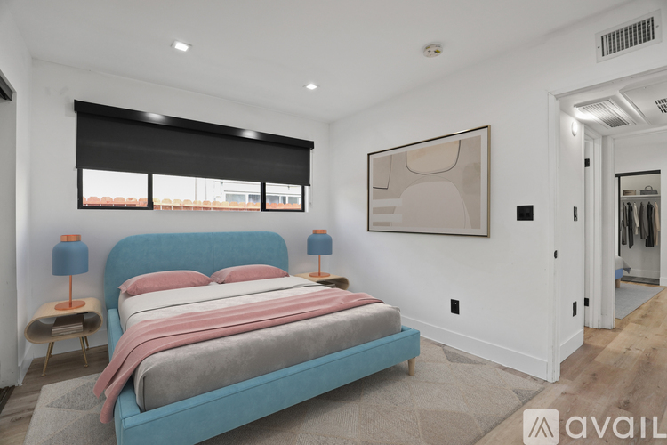 A bedroom with a blue bed and a painting on the wall.