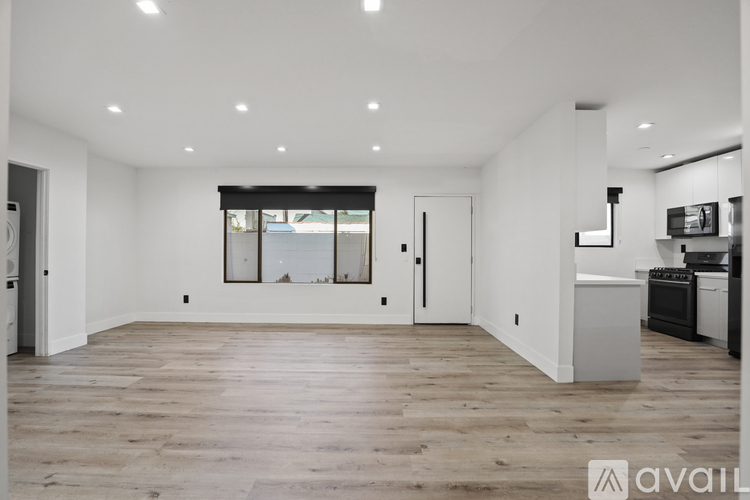 A spacious, empty room with wooden floors and white walls.