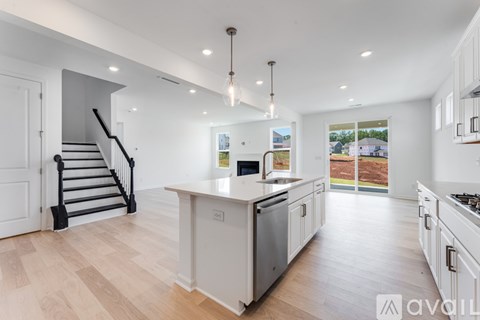 A modern kitchen with white cabinets and a wooden floor.