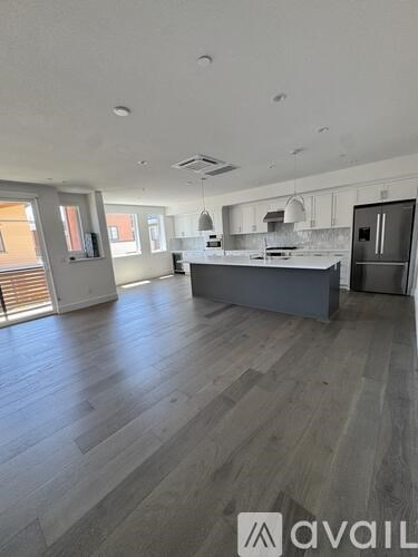 A spacious kitchen with a grey island and wooden flooring.