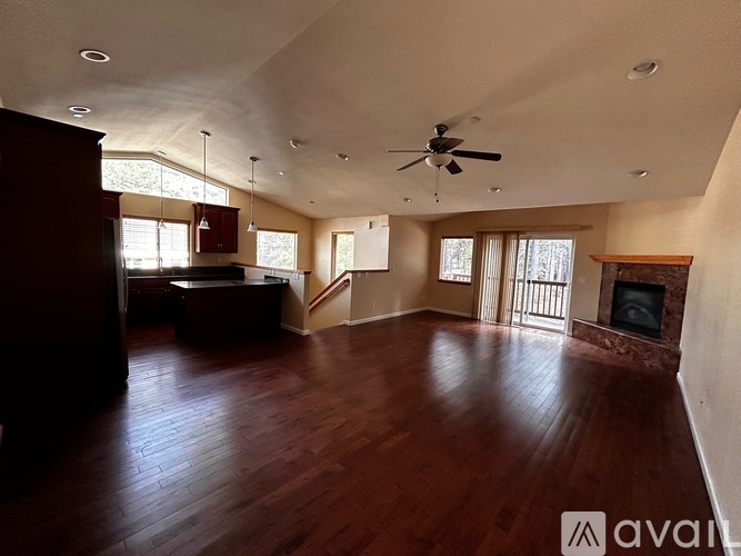A spacious living room with wood flooring and a fireplace.