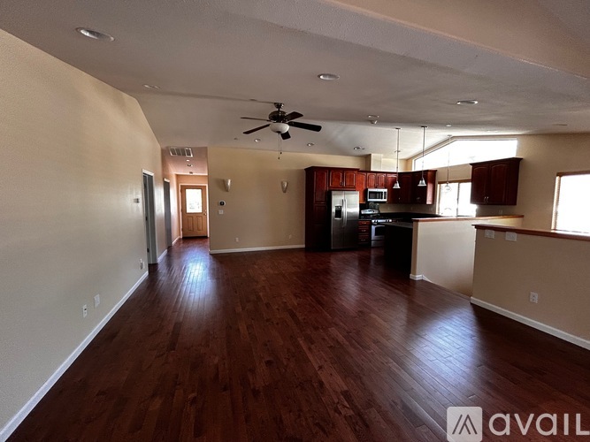 A spacious living room with wood flooring and a ceiling fan.