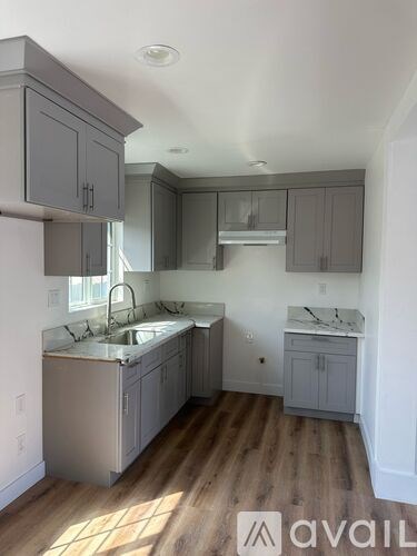 A kitchen with wooden floors and grey cabinets.