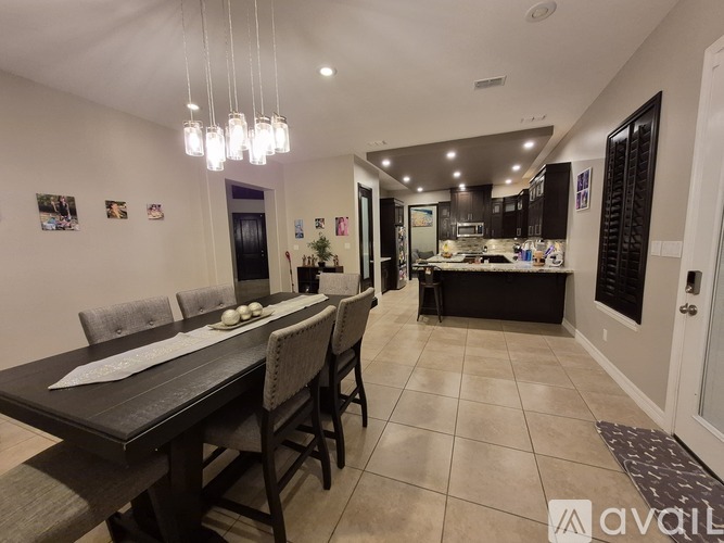 A dining room with a table set for four and a kitchen area in the background.