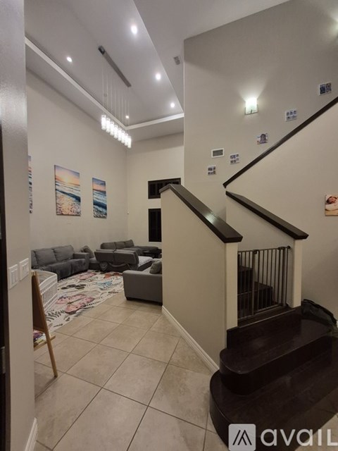 A living room with a staircase and a painting on the wall.