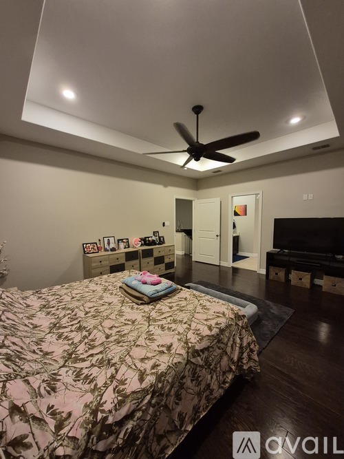 A bedroom with a bed, a ceiling fan, and a television.