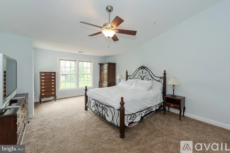 A bedroom with a large bed and a ceiling fan.