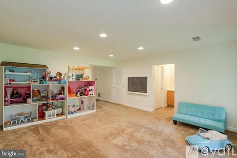A living room with a blue sofa and a dollhouse on the wall.