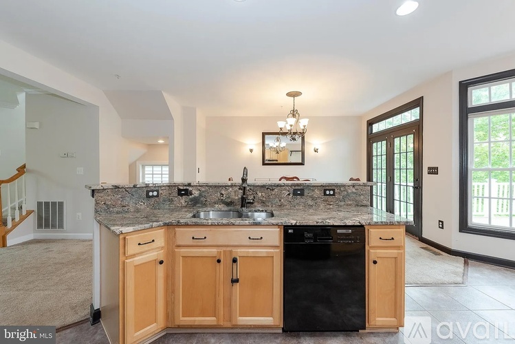 A kitchen with a black dishwasher and wooden cabinets.