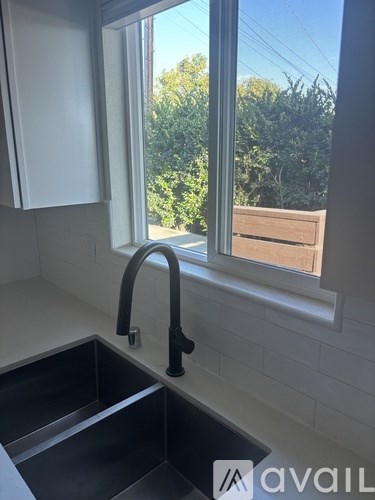 A kitchen sink with a window overlooking a wooden fence.