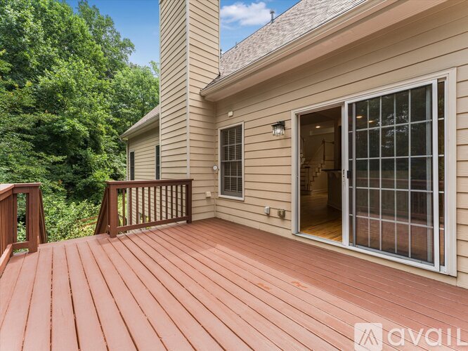 A wooden deck with a house and trees in the background.
