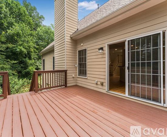 A wooden deck with a house and trees in the background.
