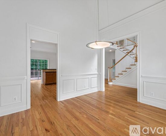 A spacious room with wooden floors and white walls.