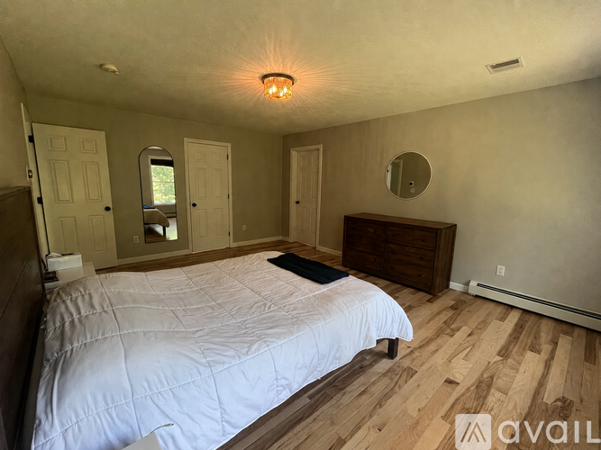 A bedroom with a large bed and wooden floors.