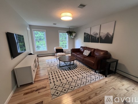 A living room with a brown leather couch and a wooden floor.